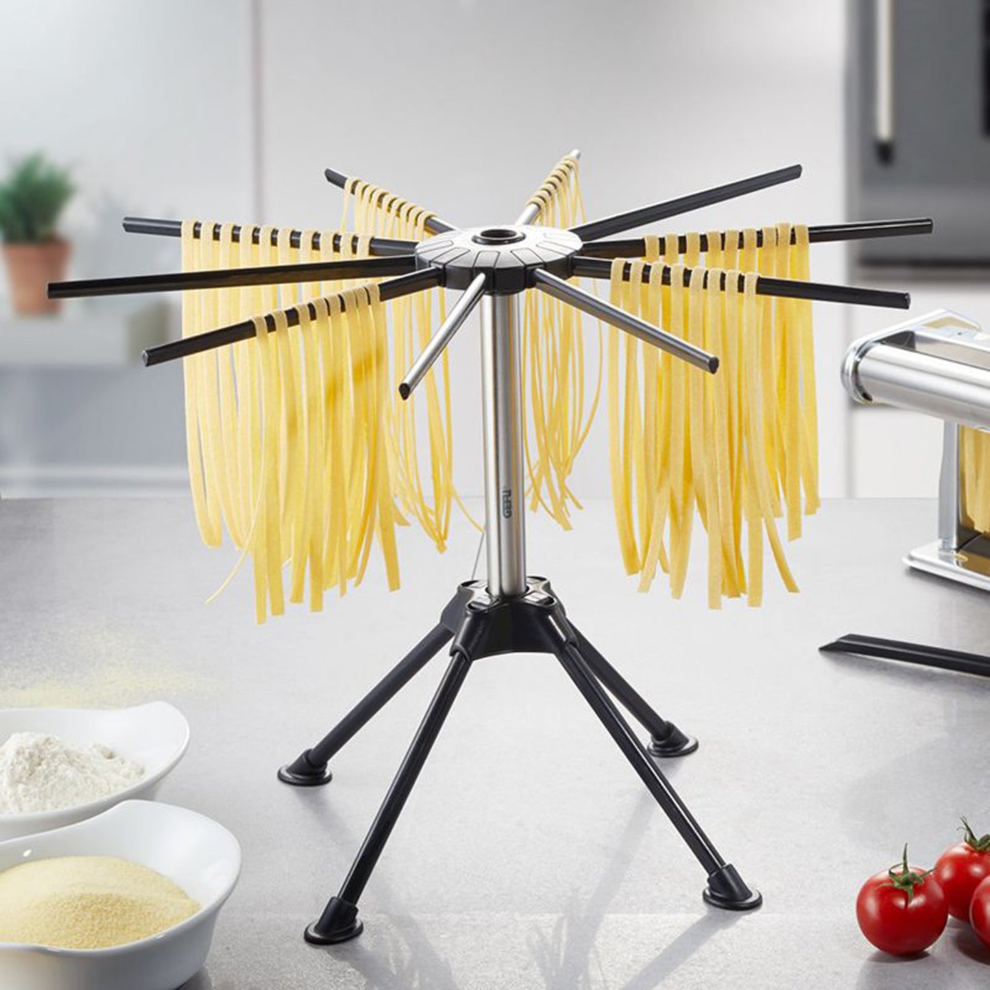 Pasta drying rack with black stand and eight arms holding yellow dry pasta strands