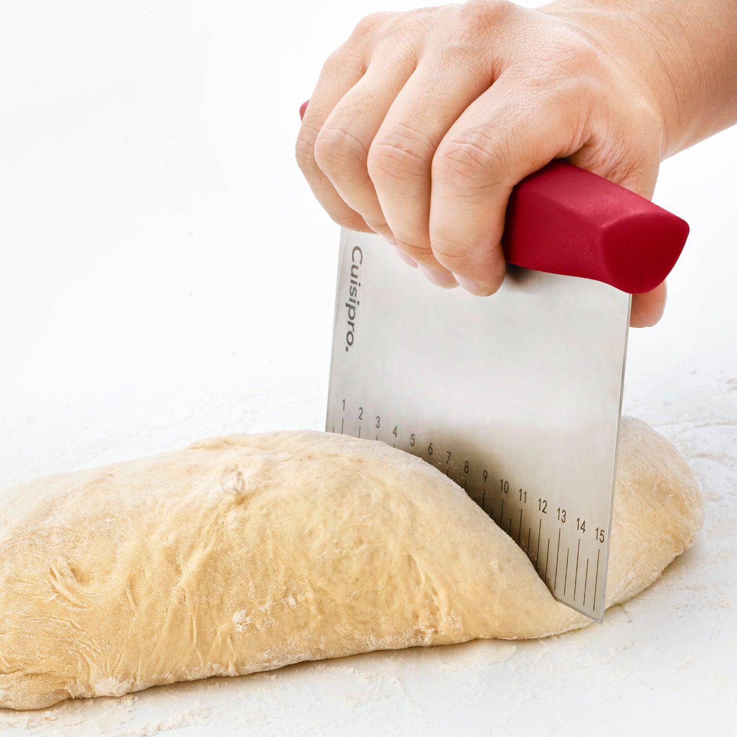 Hand holding red-handled dough cutter with numbered measuring edge for portioning
