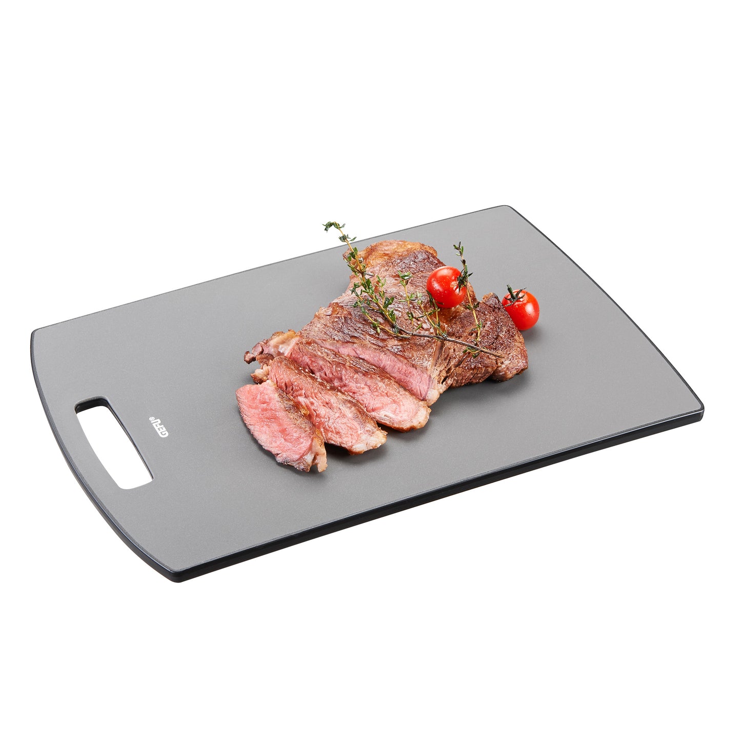 Dark gray cutting board with side hand grip, steak pieces with tomatoes and herbs
