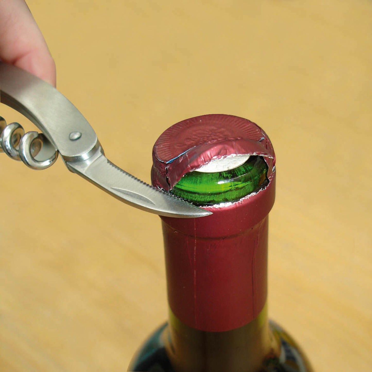 Waiter’s knife pulling a cork from a wine bottle, showing green foil