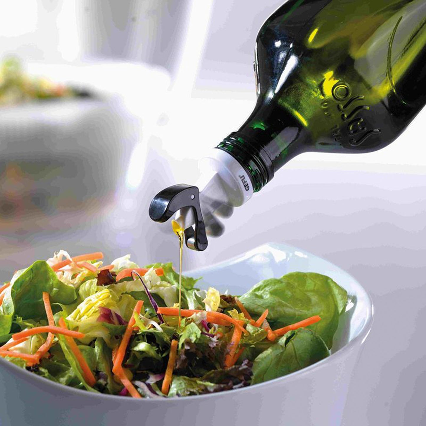 Automatic pourer dispensing oil from green glass bottle into bowl, with black lever
