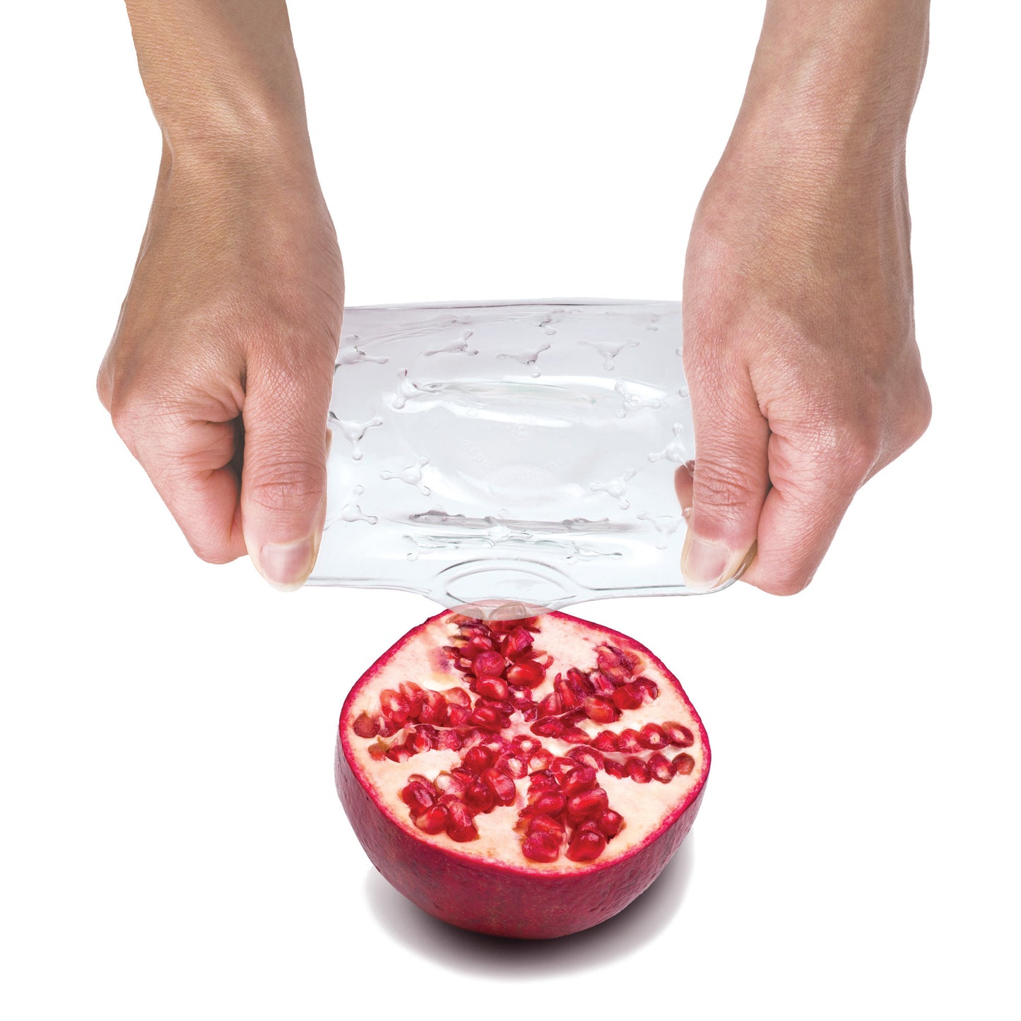 Transparent protective cover sheet over a pomegranate, held by two hands