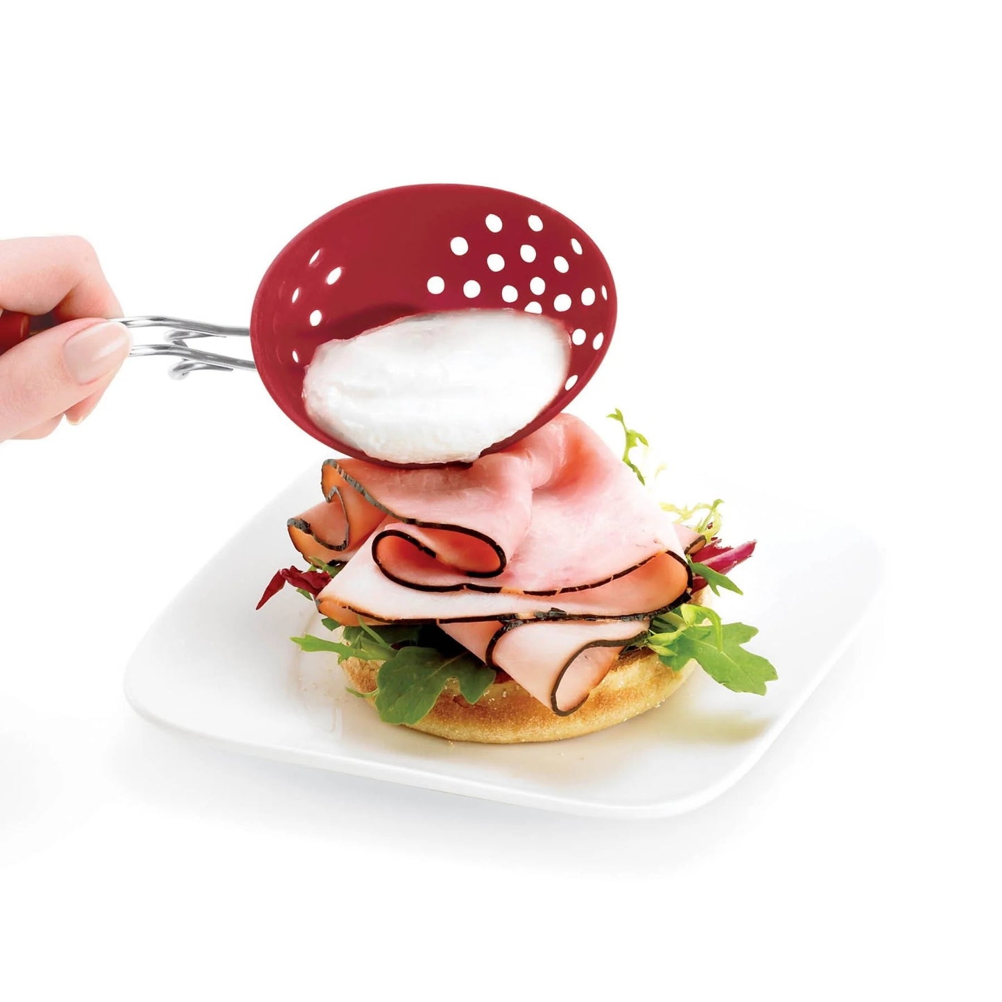 Red perforated silicone egg poacher lifting an egg over a plate