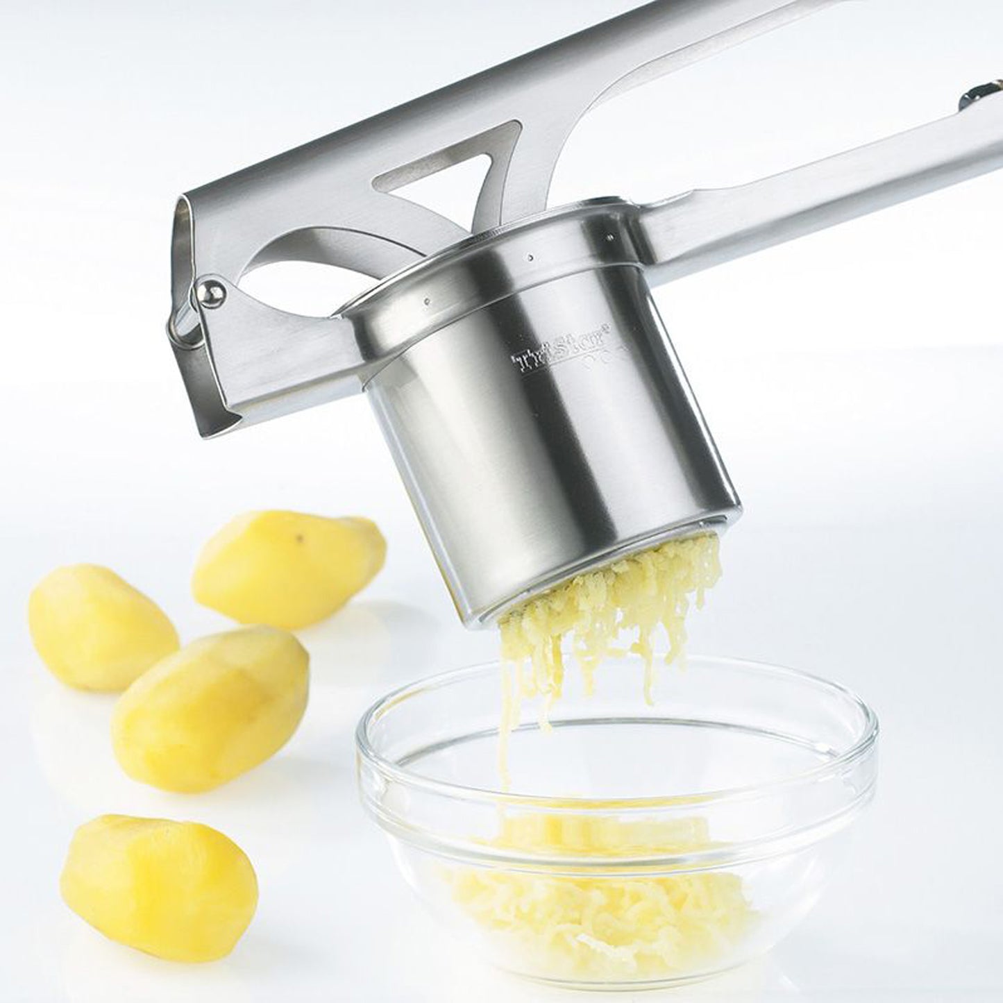 Stainless steel potato & spaetzle press over a bowl with grated strands