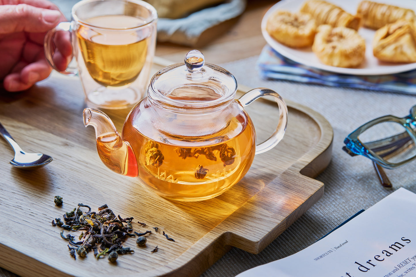 Glass teapot with amber tea and integrated glass infuser, clear lid and curved handle
