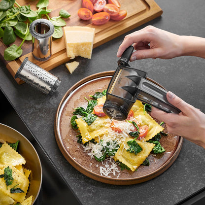 RULLARE rotary grater releasing cheese over ravioli while held by a hand