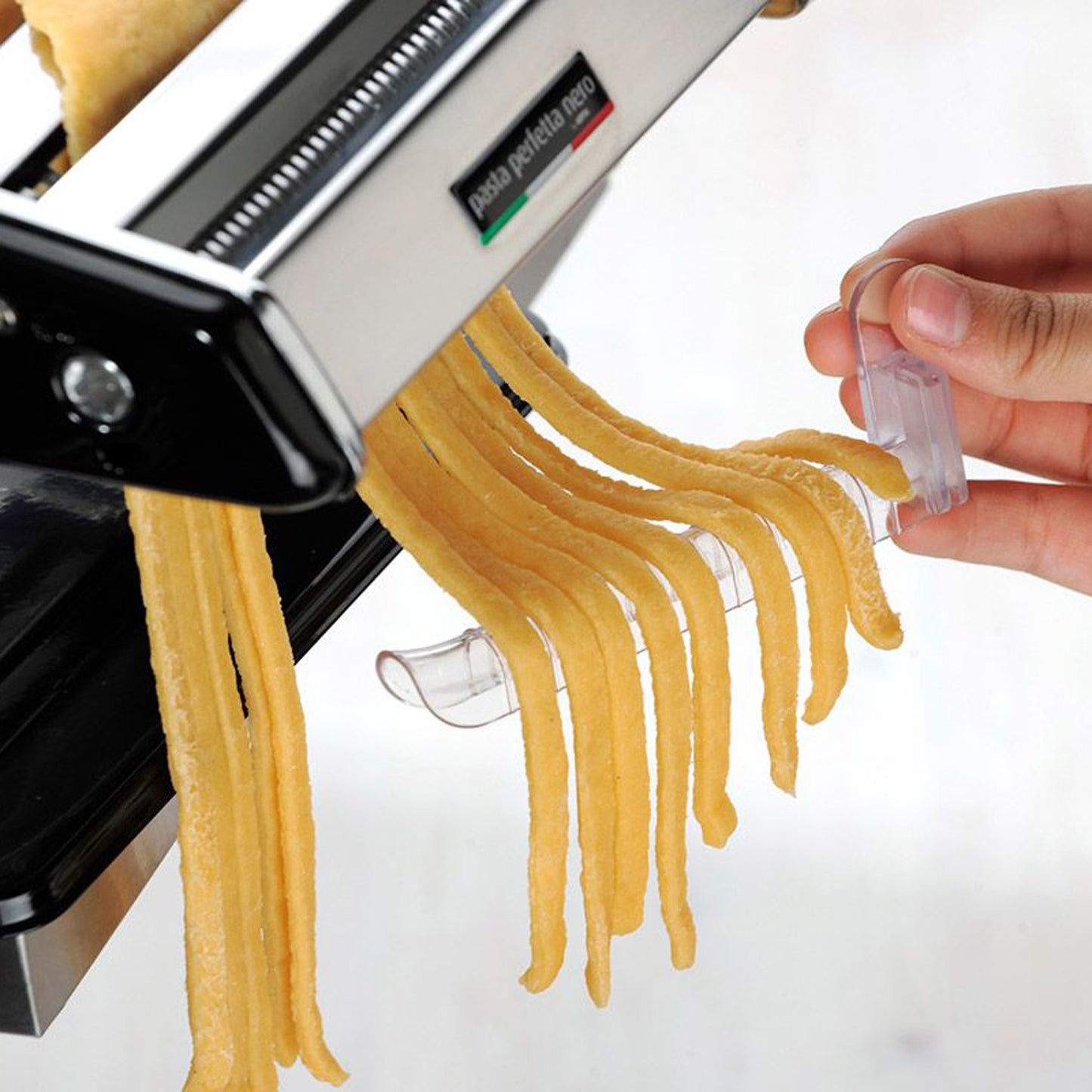 Pasta dryer close-up: hand secures yellow spaghetti onto white clip rack