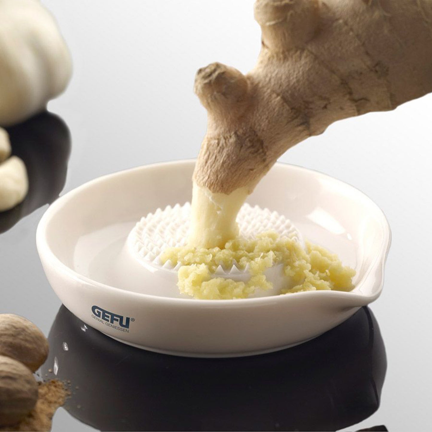 Ginger grater with grated ginger in white bowl on dark base, GEFU