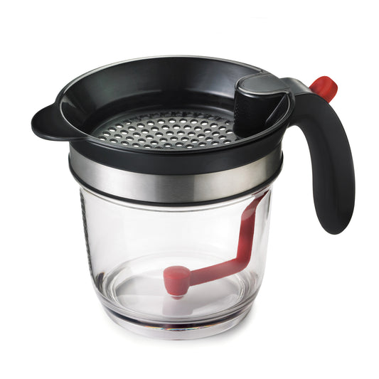 Fat separator cup with black strainer lid and red draining lever, clear glass body