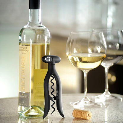 Black corkscrew with spiral worm beside bottle and wine glass, holding a cork