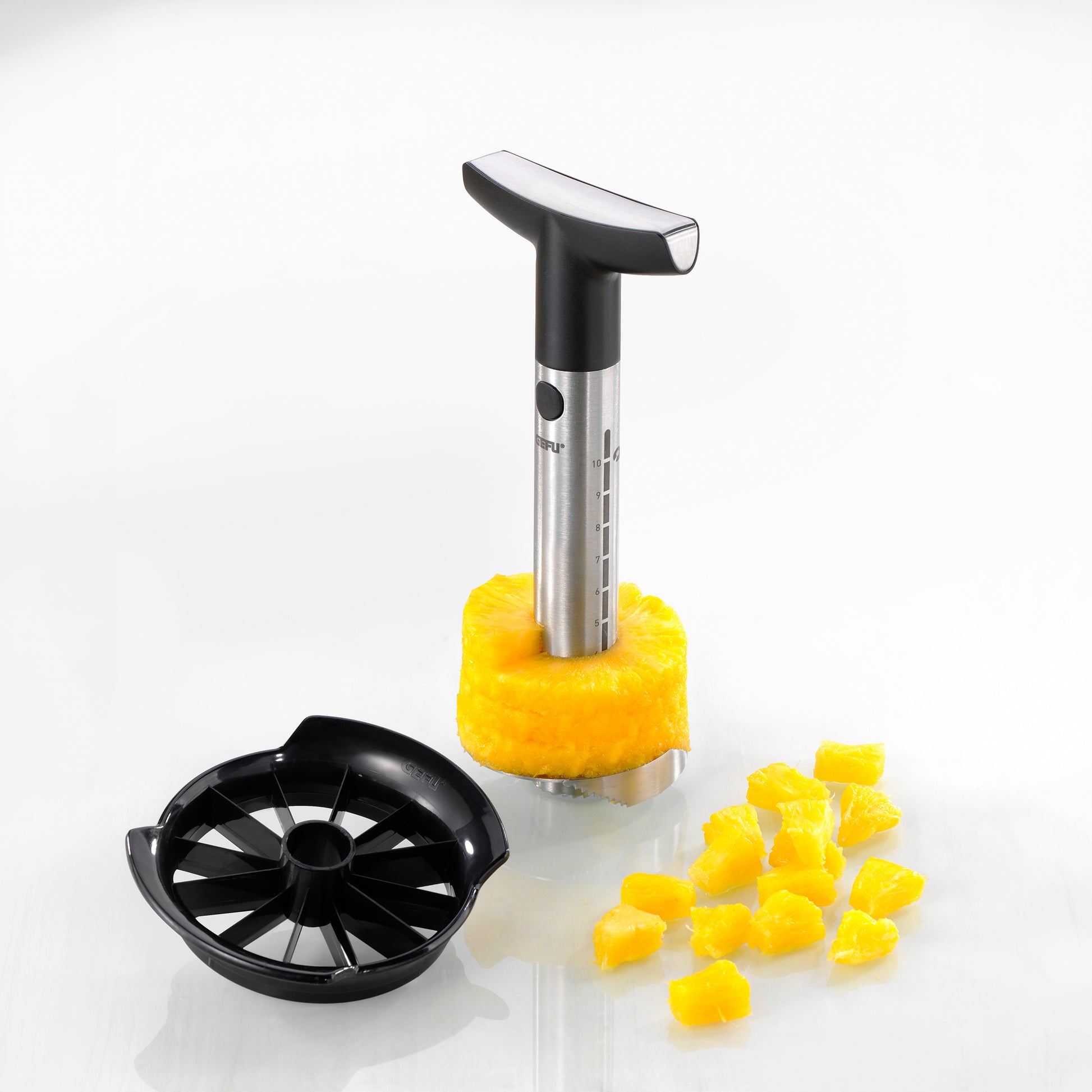 Pineapple slicer with metal coring handle, black base, and sliced pineapple pieces