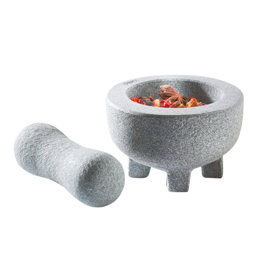 Grey granite mortar with pestle, filled with spices and seeds