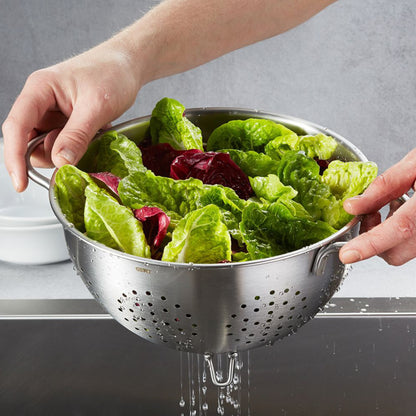 COLINO Stainer perforated colander held by hands, leafy greens inside, draining
