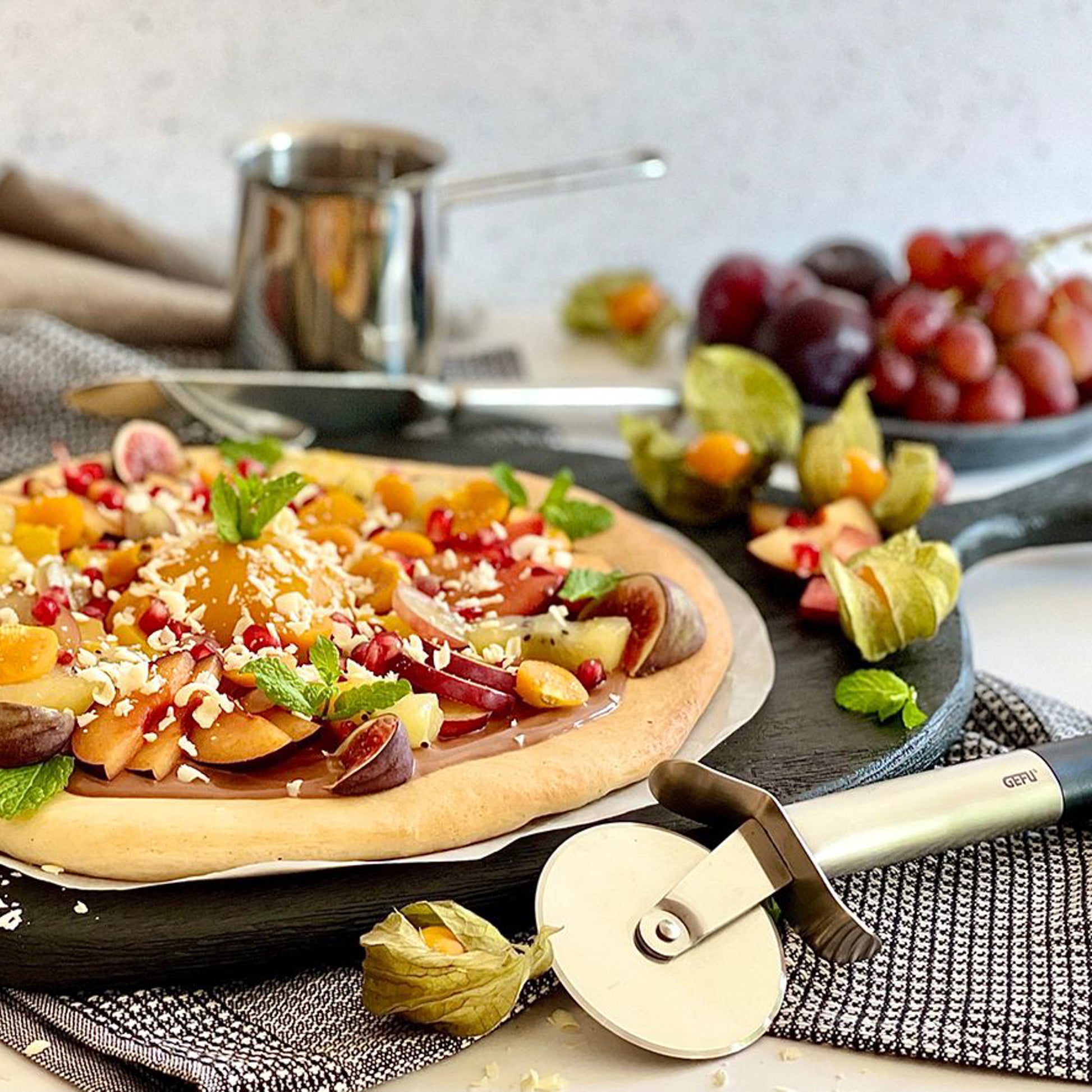 Pizza cutter wheel cutting a topped pizza on a kitchen counter