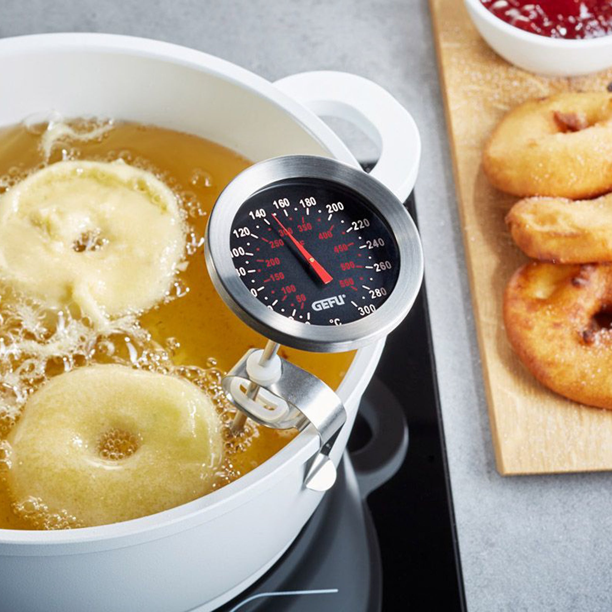 Cooking thermometer clipped to a pot with round stainless dial and red temperature scale