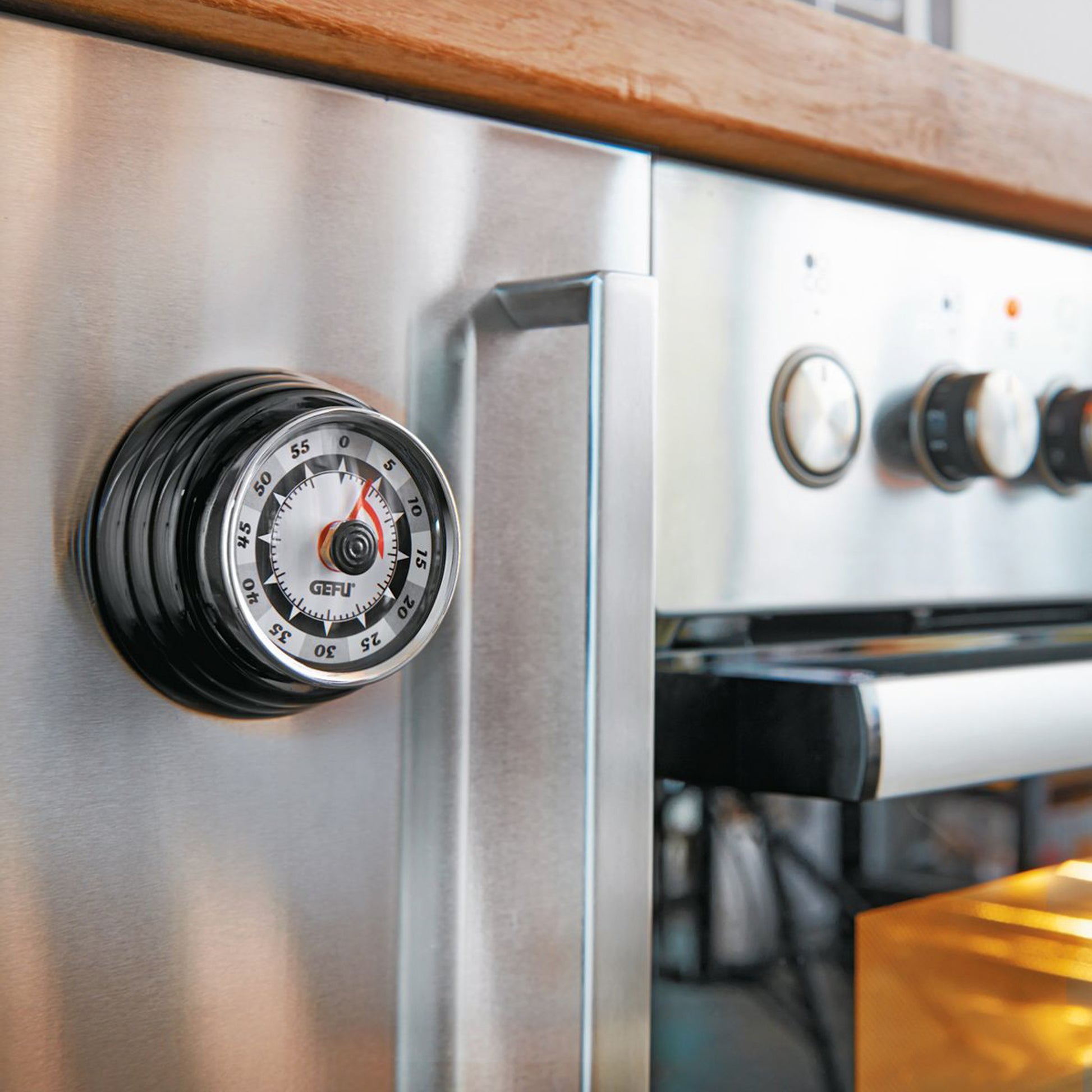 Retro timer on metal appliance door, black dial with orange indicator