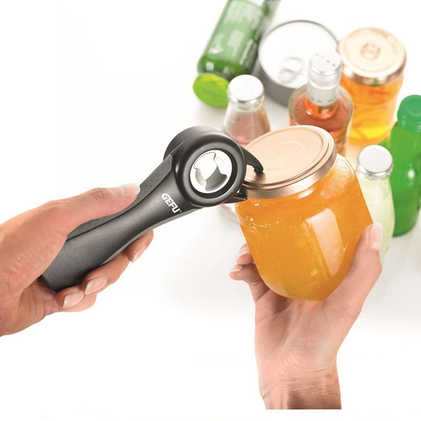 Black opener held in hand lifting a jar lid with multi-tool head; bottles nearby