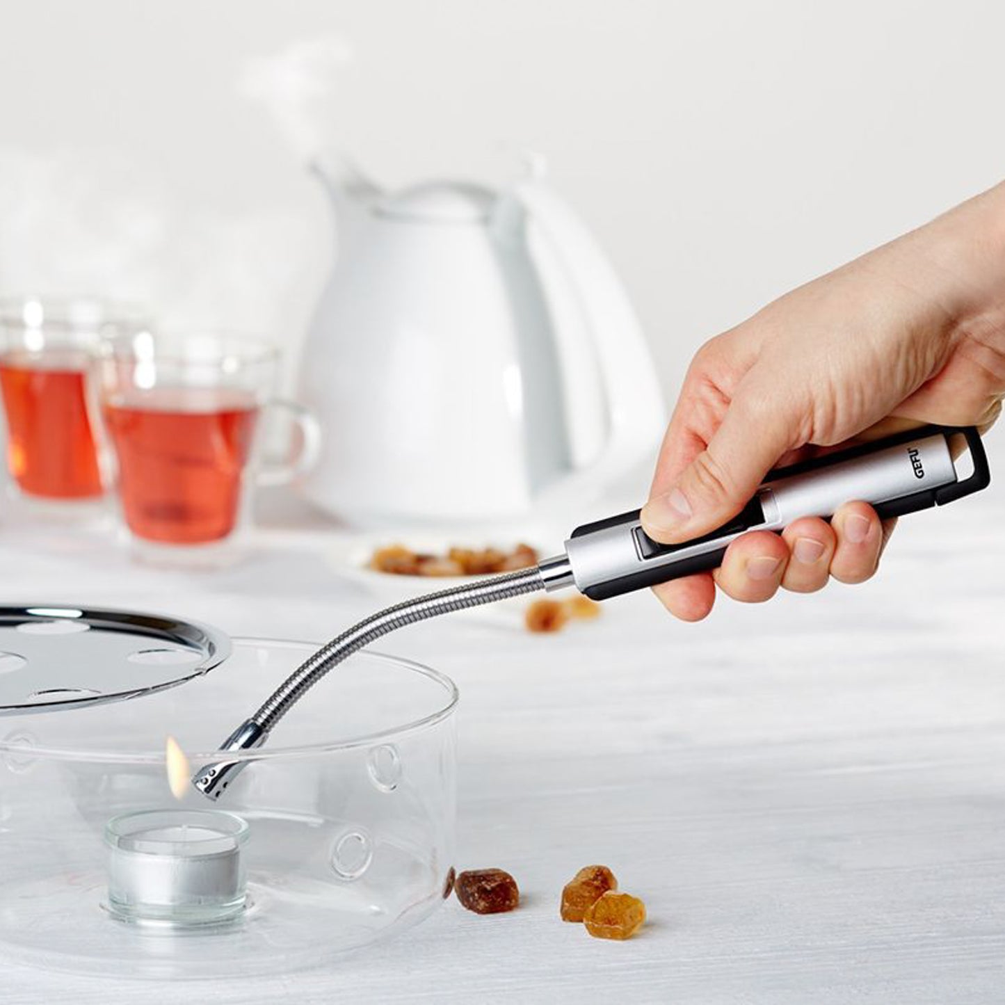 Hand-held long lighter with silver spout lighting a small flame