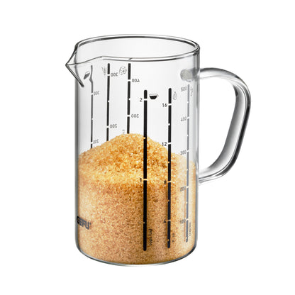Clear measuring jug with spout, handle, and ml markings; filled with orange grains