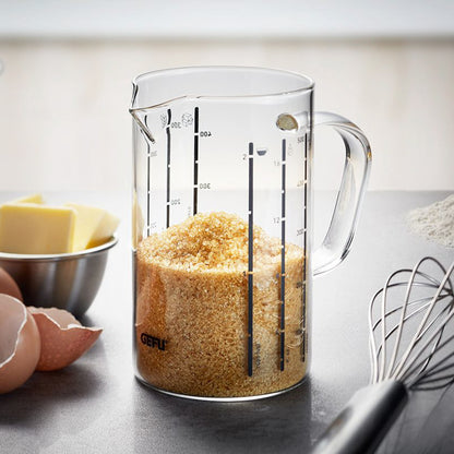 Clear measuring jug with spout and handle, showing ml and L markings; filled with golden grains