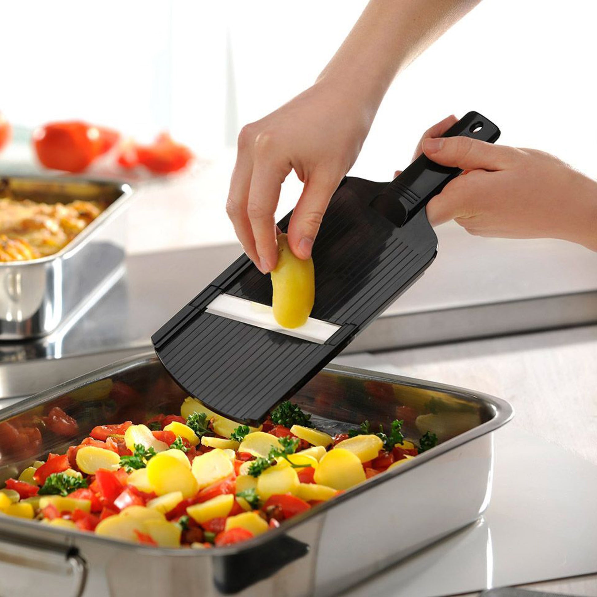 Hands using ceramic slicer with black handle to slice vegetables on a tray