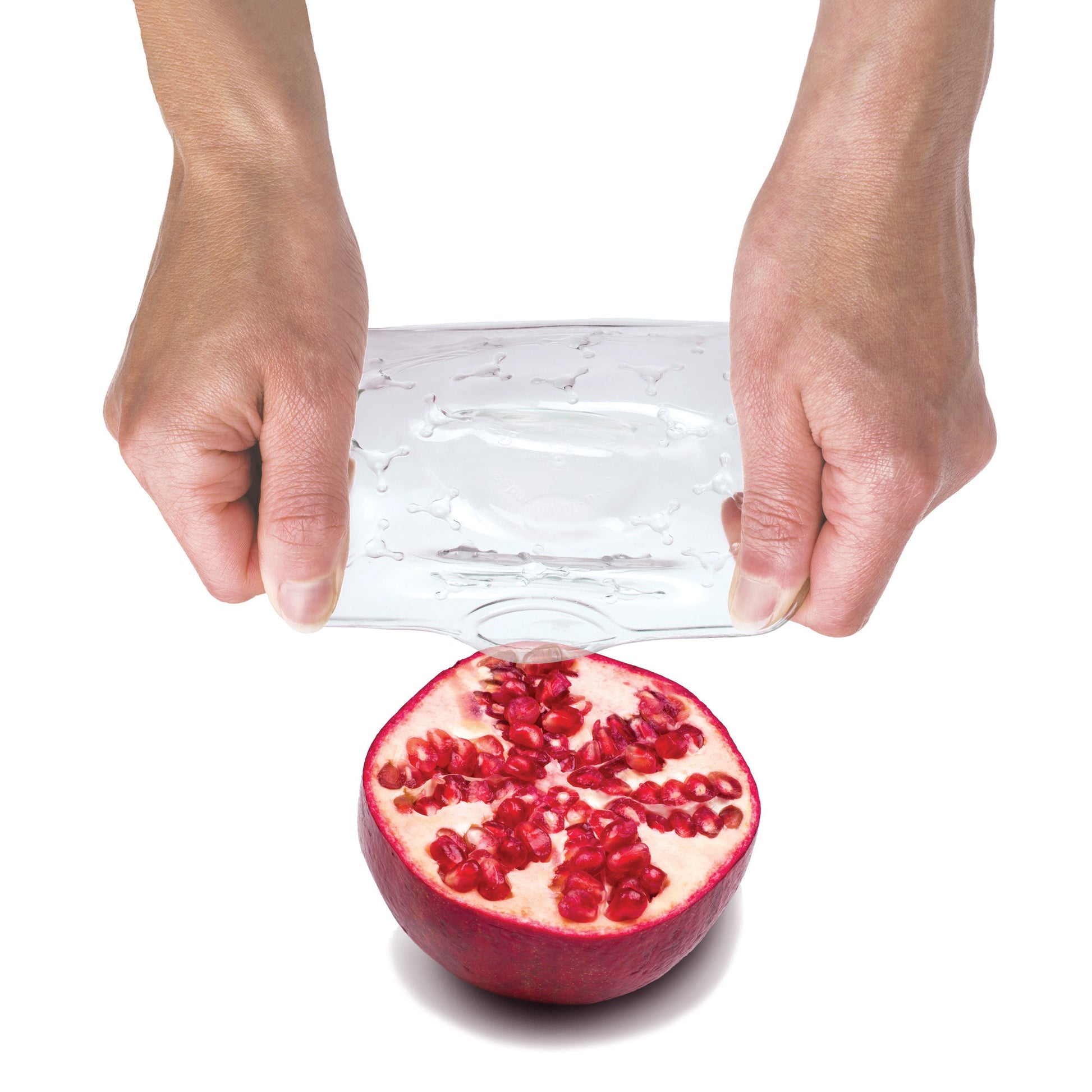 Transparent protective cover sheet over a pomegranate, held by two hands