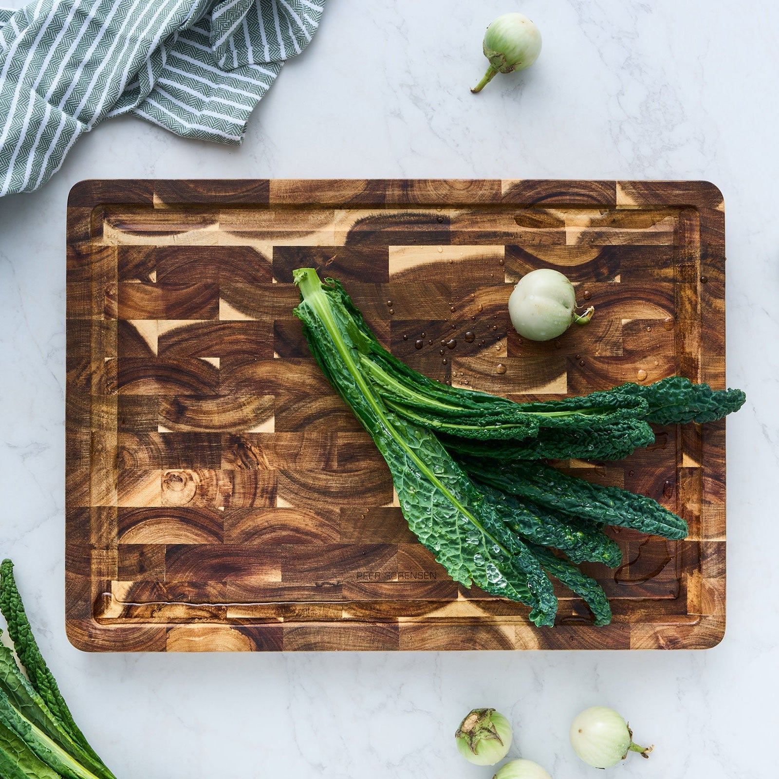Wooden cutting board with green leafy vegetables on a light gray surface
