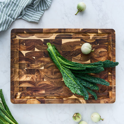 Wooden cutting board with green leafy vegetables on a light gray surface