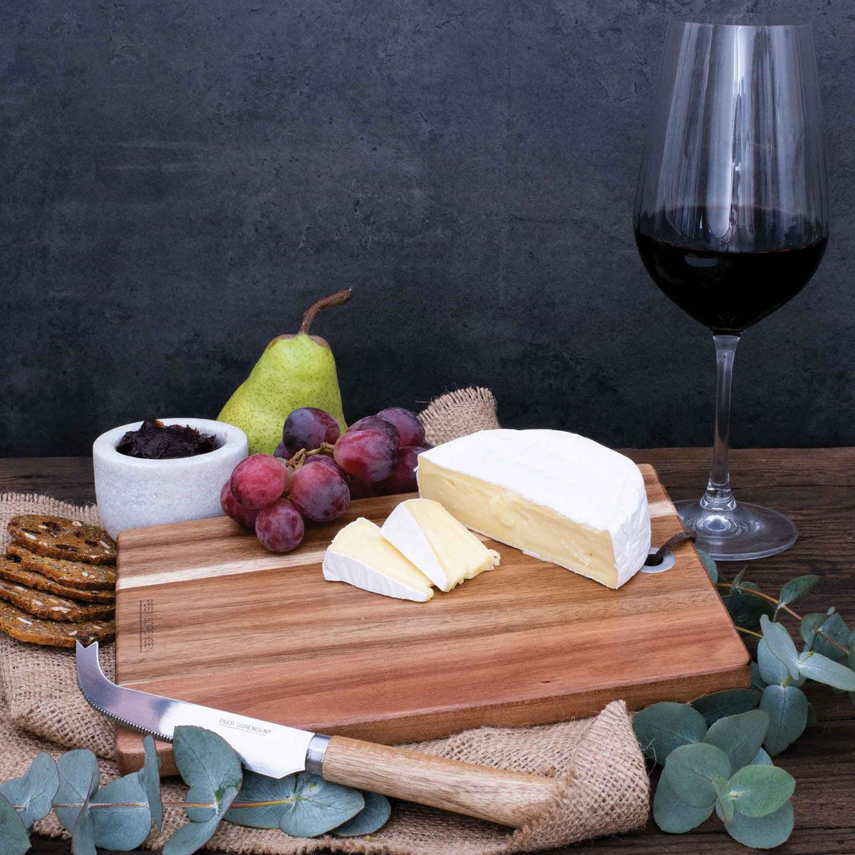 Rectangular wooden cheese serving board with serrated cheese knife and cheese wedges
