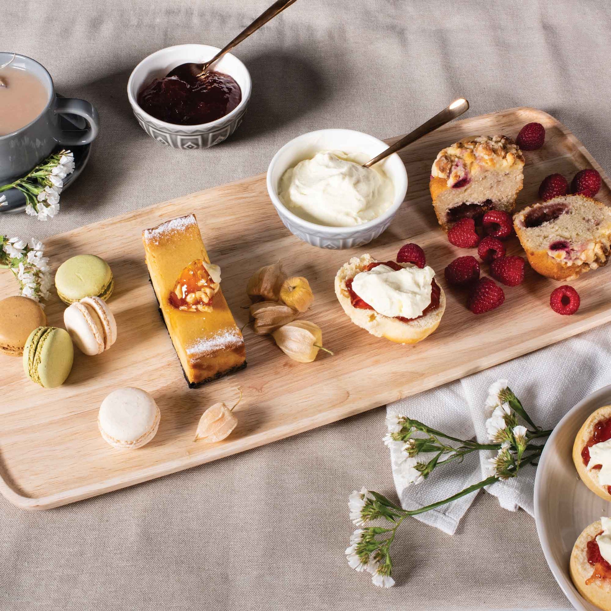 Rectangular wooden serving platter with desserts, fruit, and bread items