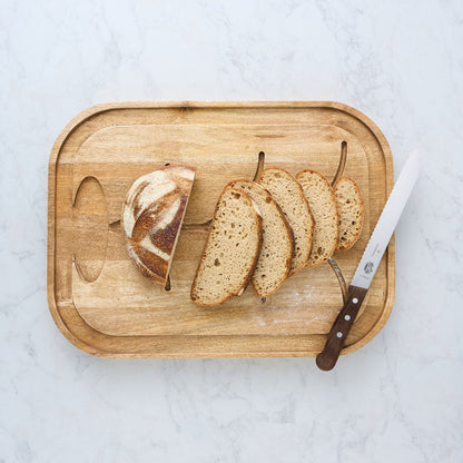 Mangowood cutting and serving board with sliced bread and a chef knife