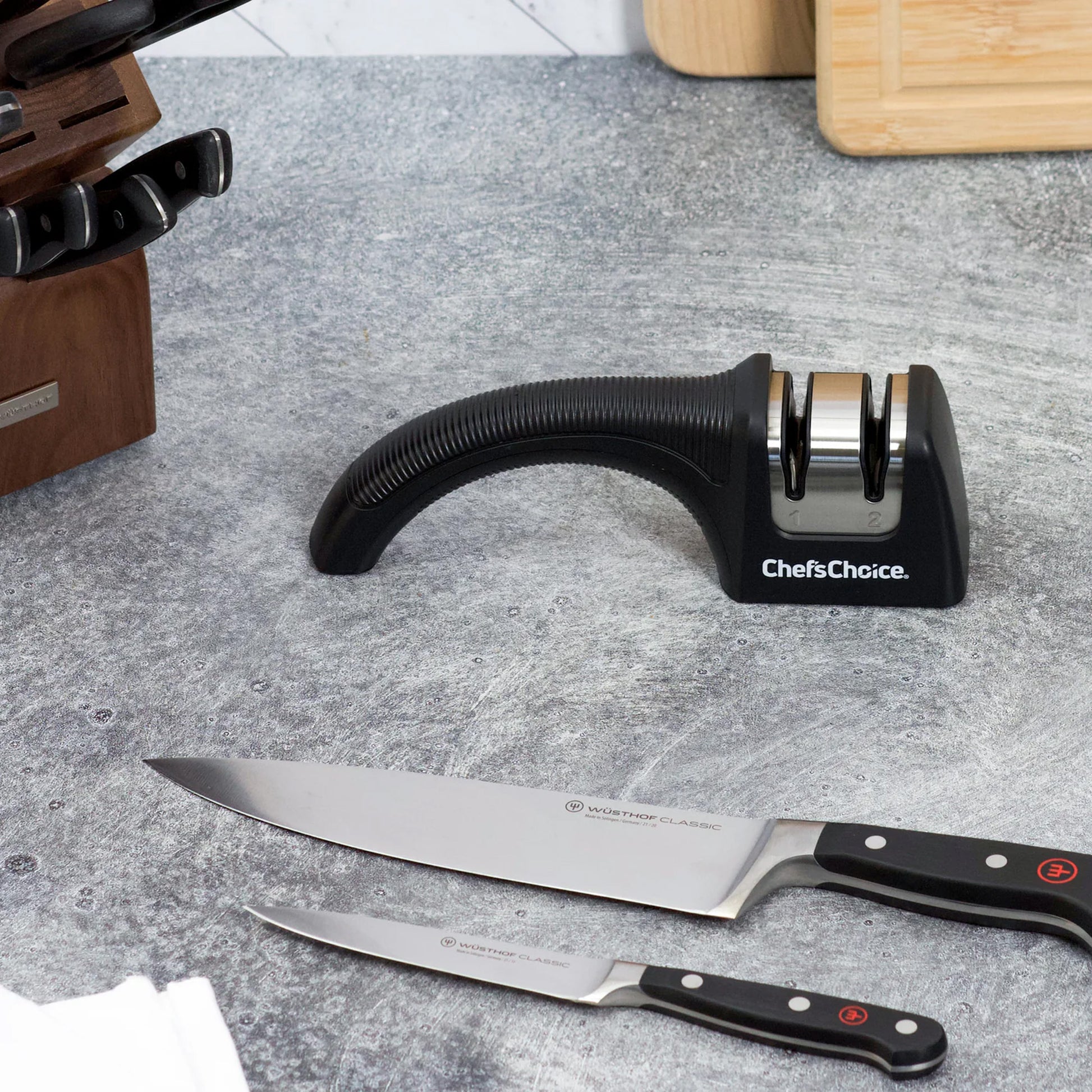 Chef'sChoice diamond hone knife sharpener beside two kitchen knives with black handles