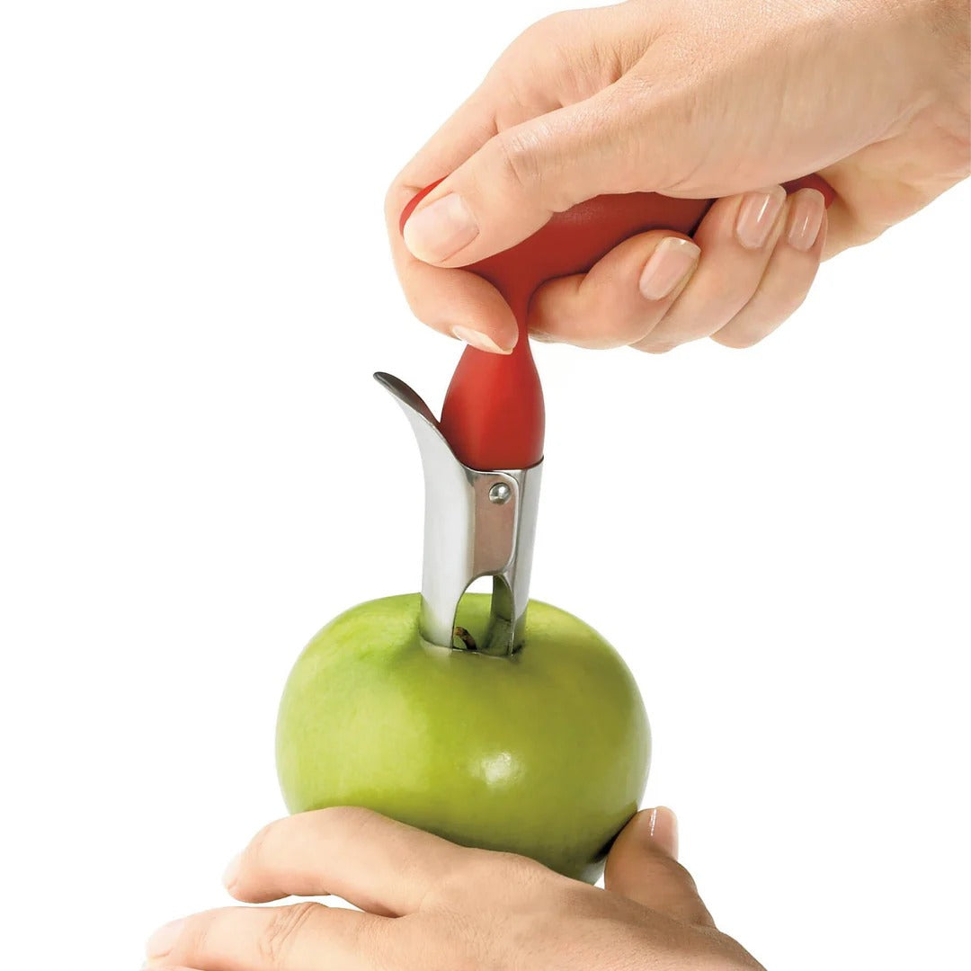 Apple corer inserted into a green apple with red handle held by hands
