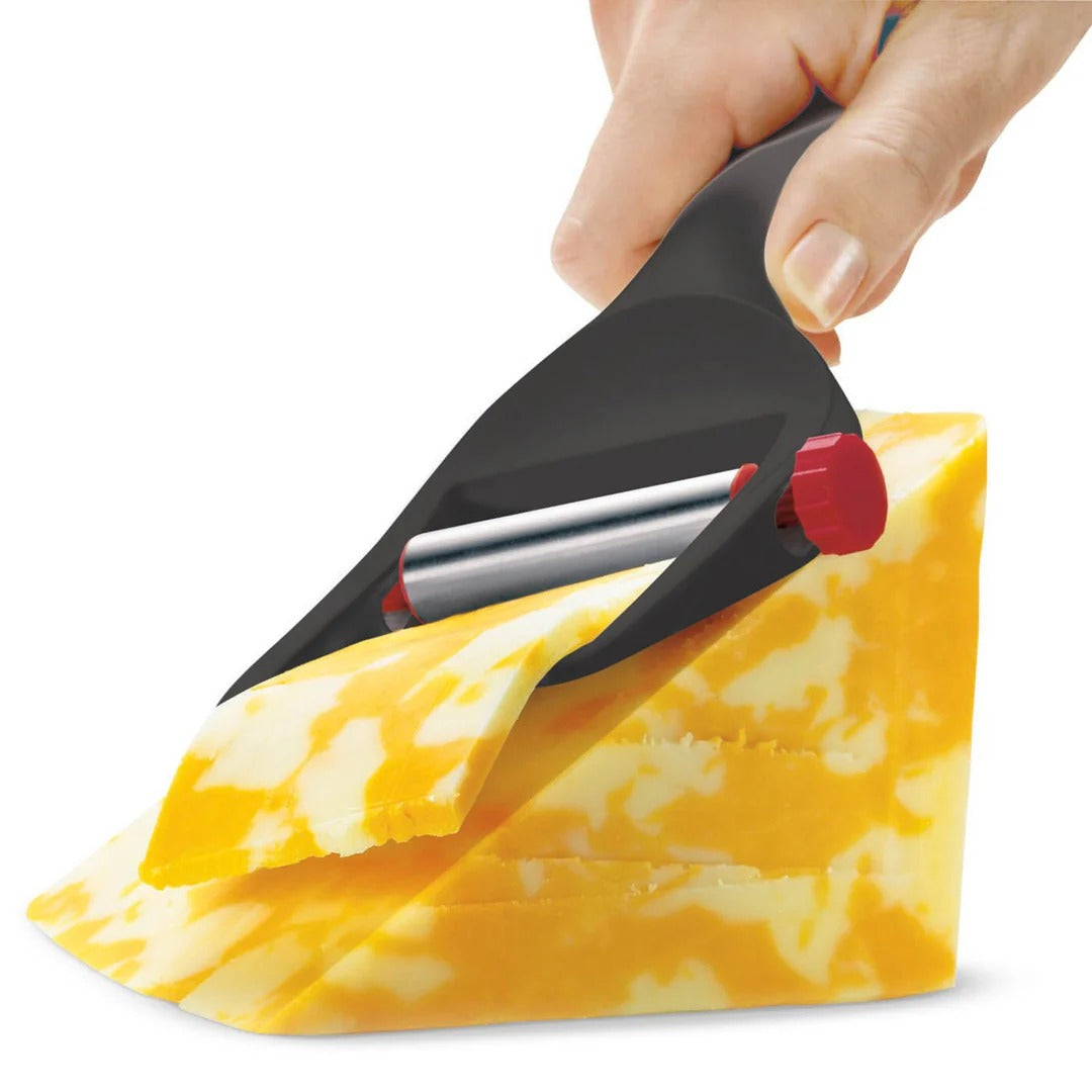 Hands using black adjustable cheese slicer to cut cheese wedge; red control knob