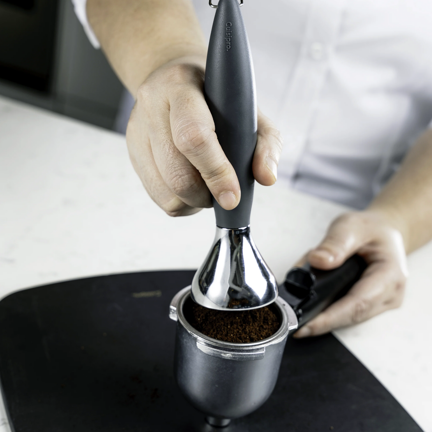 Coffee tamper with dark handle tamping coffee grounds