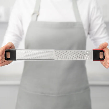 Grater held horizontally by hands over a white apron