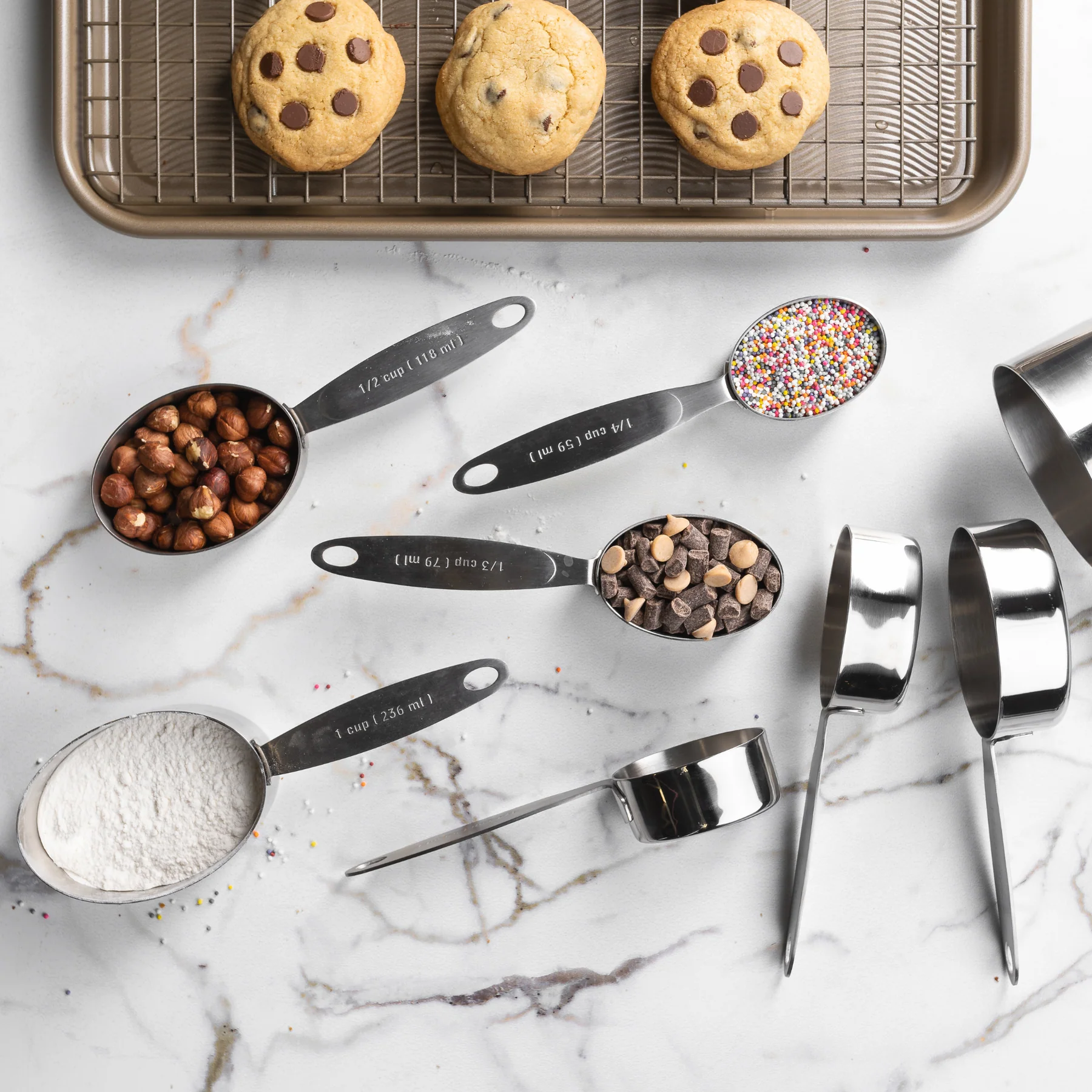 Four-piece stainless steel measuring cups and spoons on kitchen surface