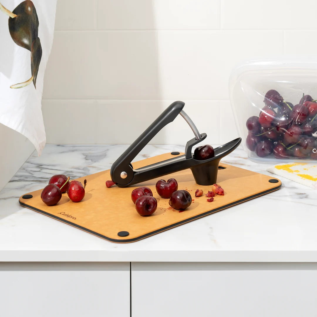 Handheld cherry and olive pitter with clamp handle and red collection cup