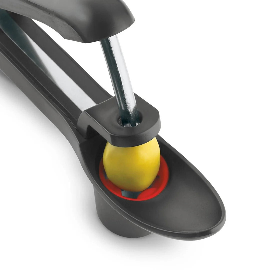 Close-up of dark gray cherry and olive pitter mechanism and red capture cup