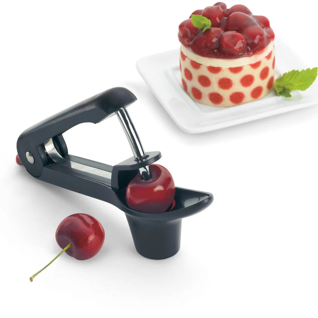 Handheld cherry and olive pitter releasing a pitted cherry into the red cup