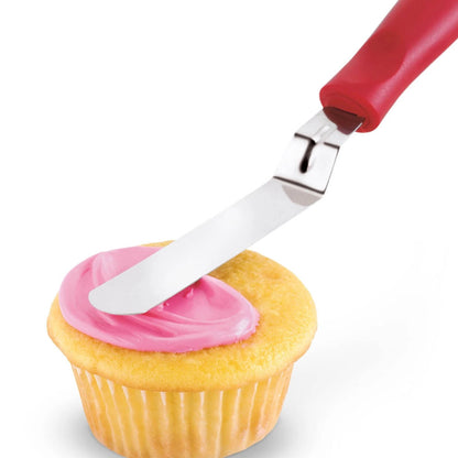Icing spatula spreading pink frosting on a cupcake