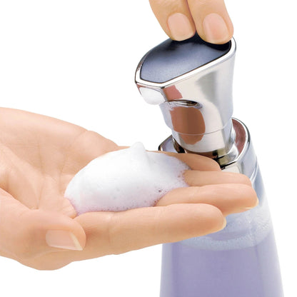 Foam pump dispenser with chrome head; hands pressing to dispense white foam