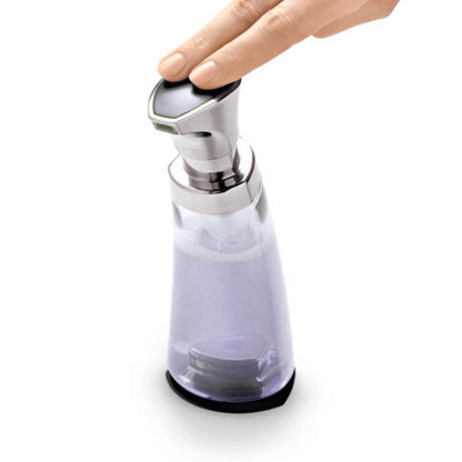 Foam pump dispenser with chrome lever; hand pressing to dispense over clear container